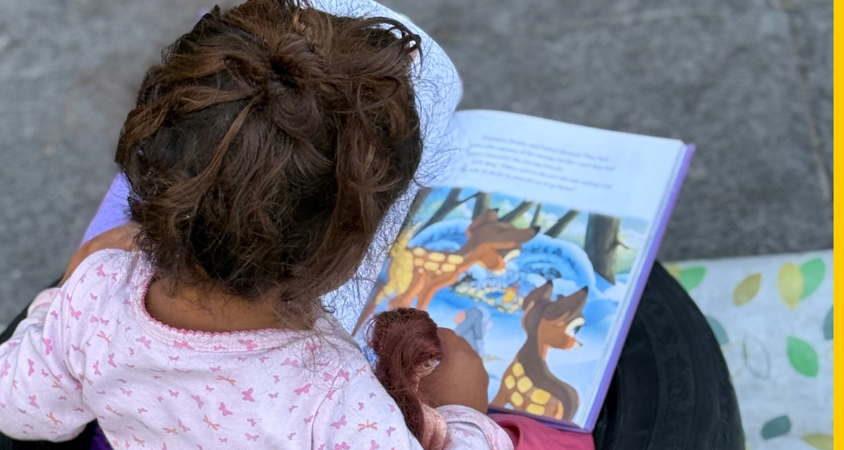 A toddler reading a picture book while seated in a repurposed tire
