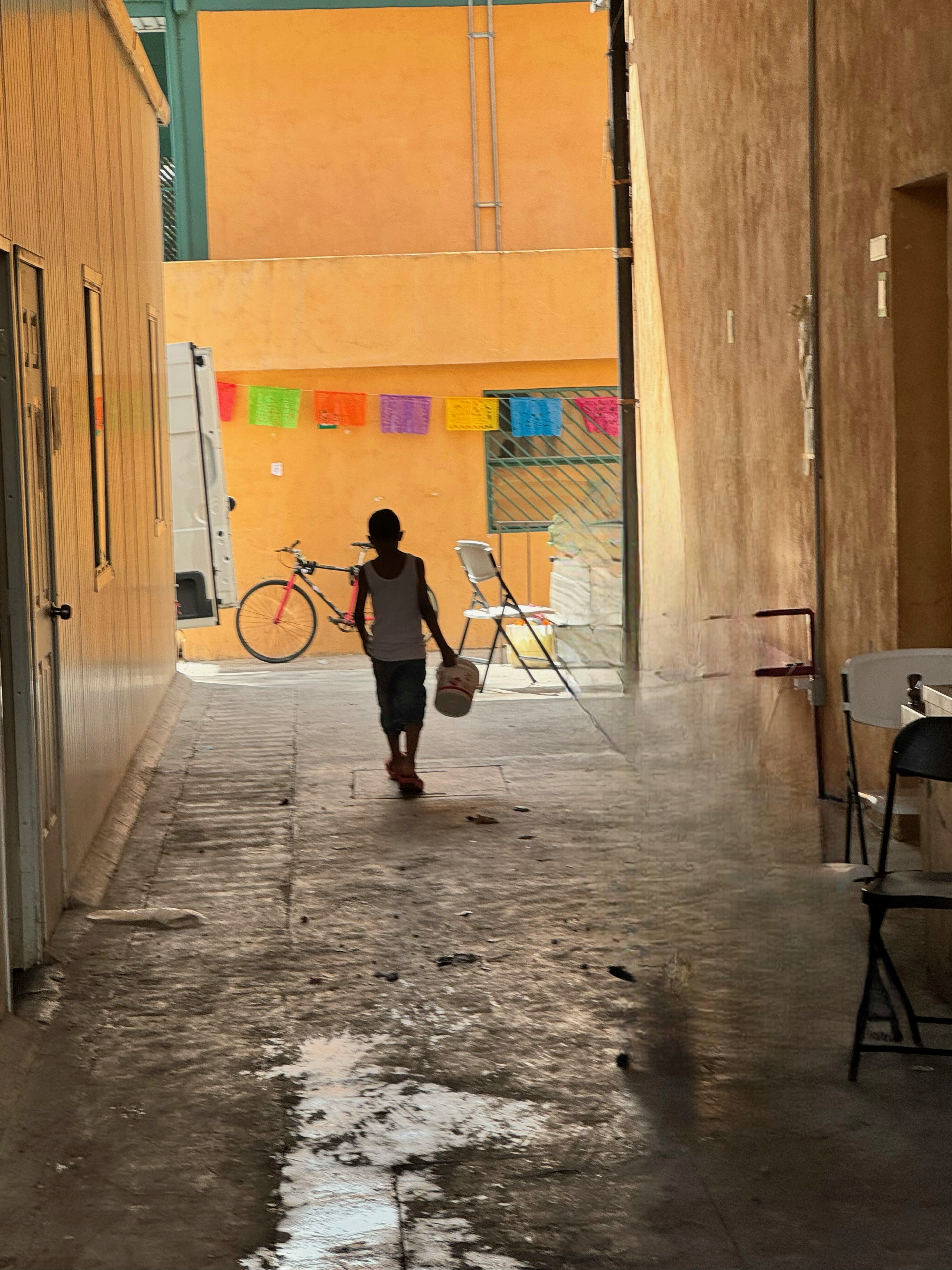 A boy walking through a migrant encampment alley