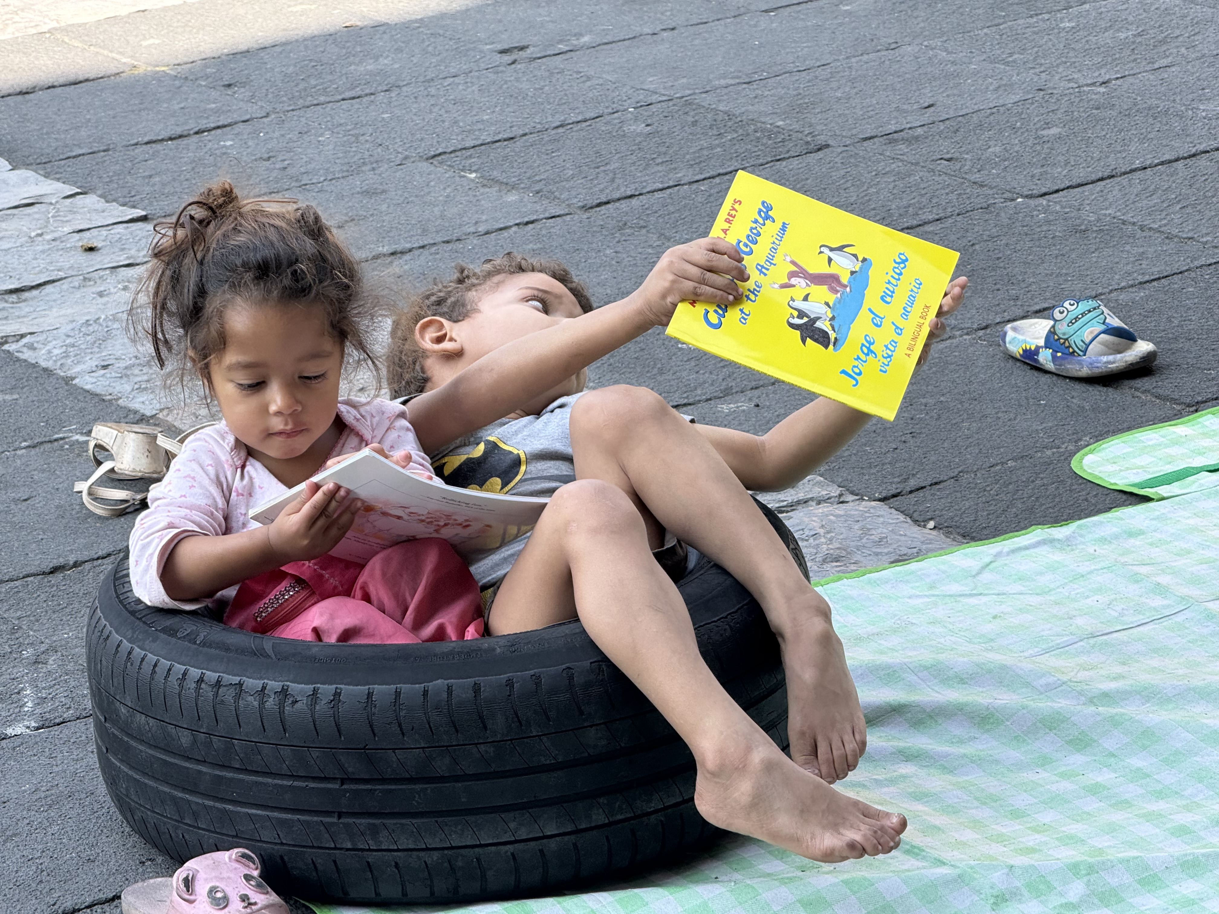 Two children reading a bilingual book together in a tire seat