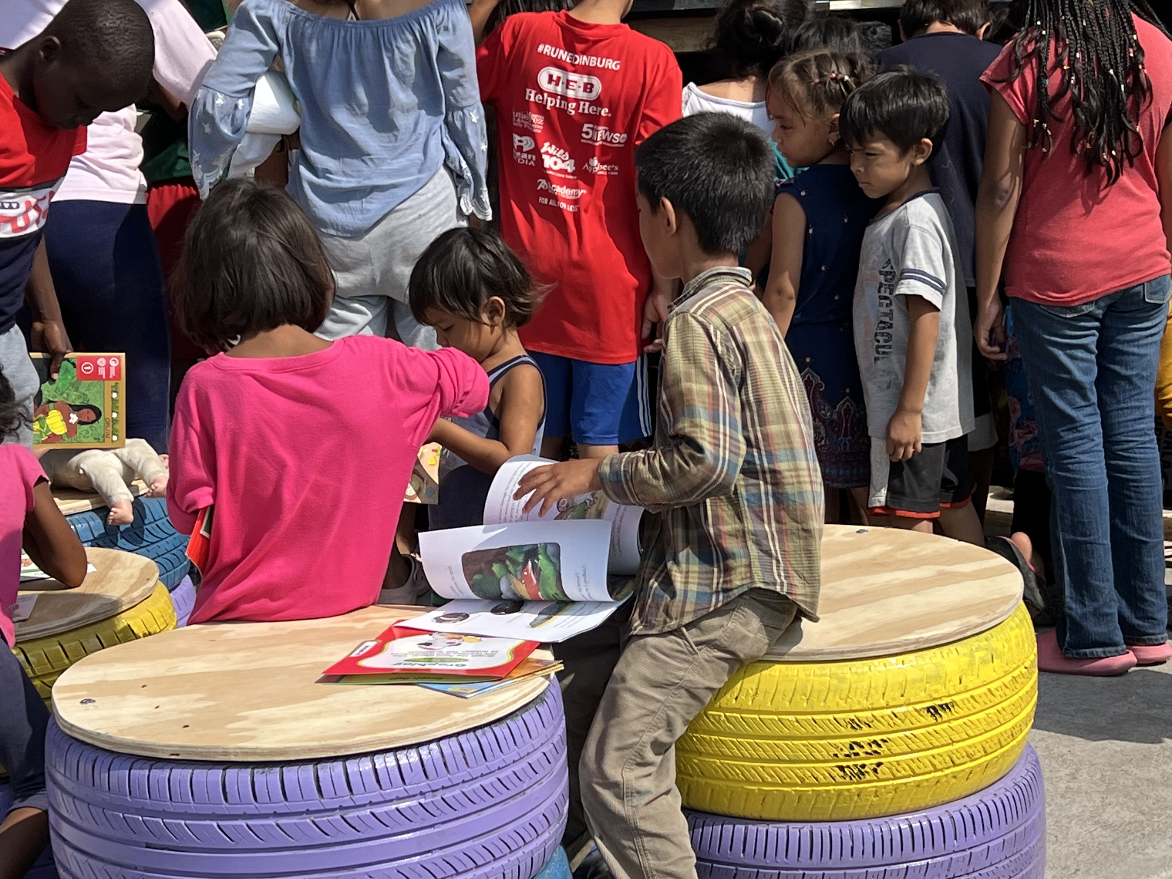 Children reading books together on colorful tire seats