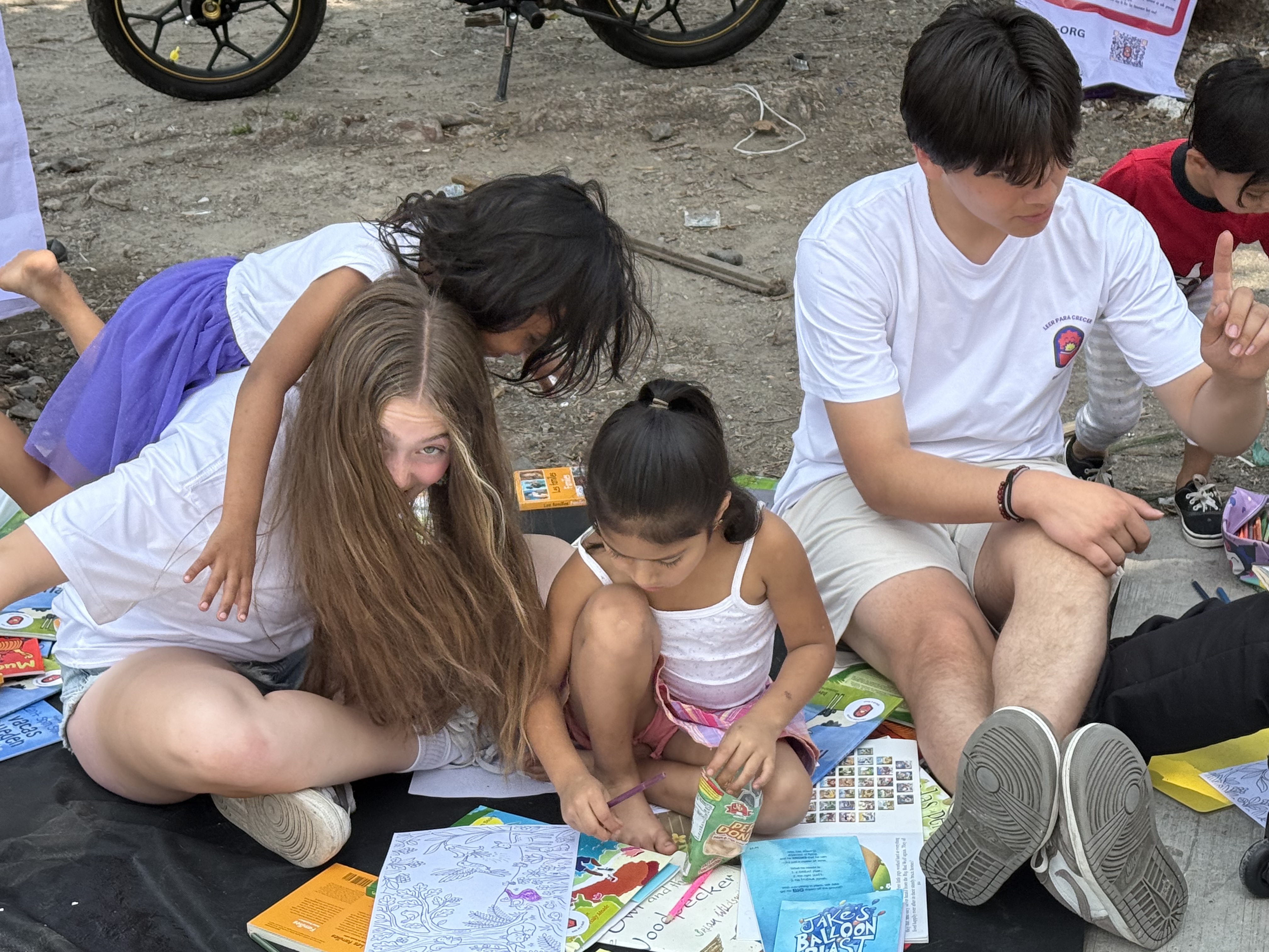 Student volunteers and children reading and coloring books together